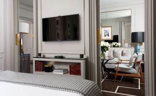 Bedroom in grey tones with grey and white houndstooth throw and looking through to the lounge area