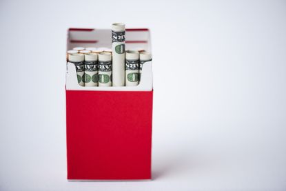 Red cigarette package with rolled up US dollars
