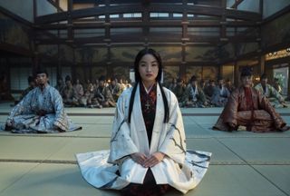 a woman (anna sawai as toda mariko) sits in front of a room of japanese feudal nobles, in shogun