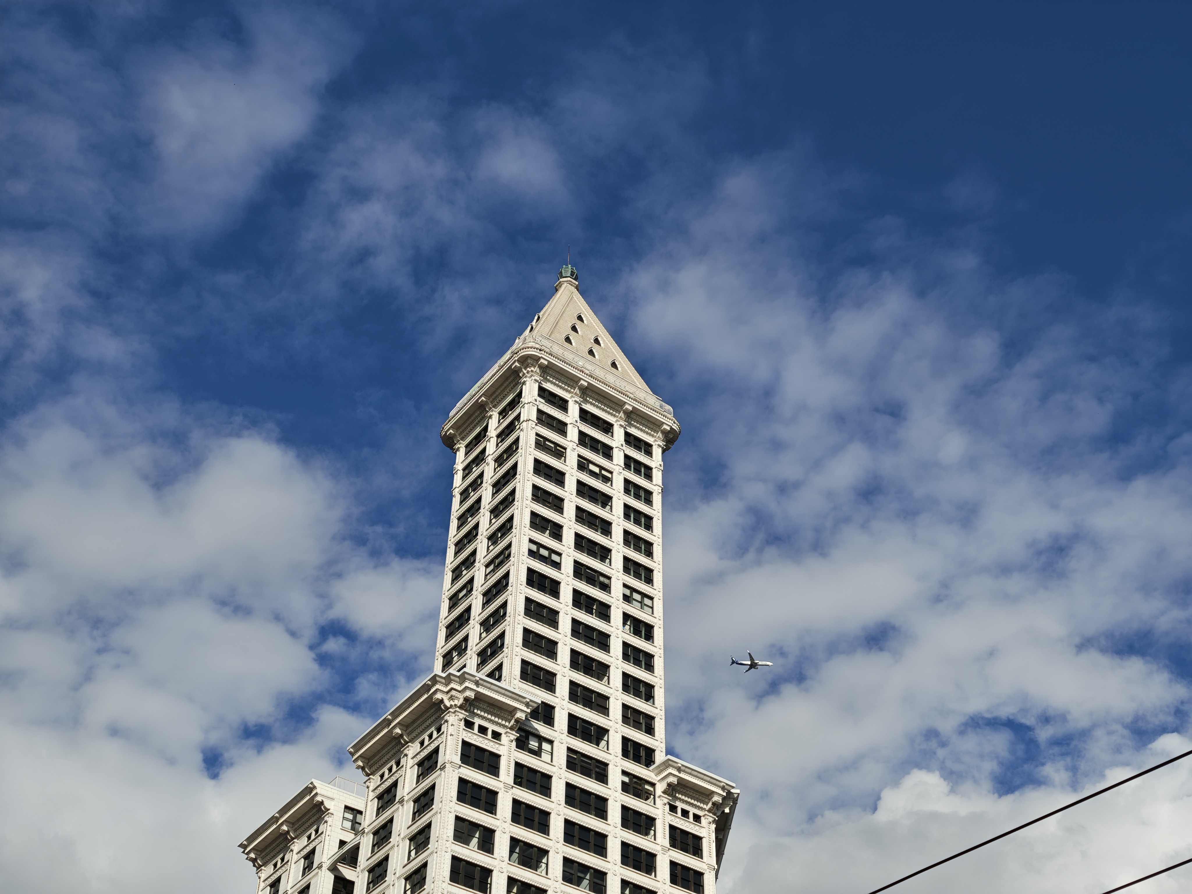 A white building with a plane flying nearby