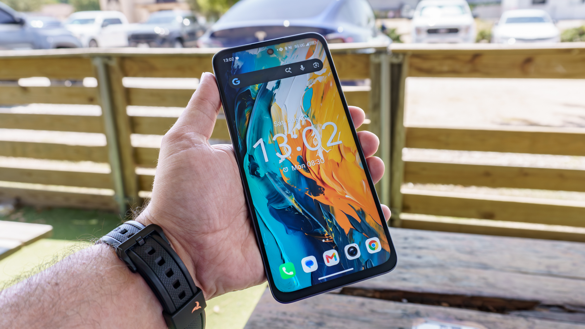 A person holding the TCL NXTPAPER 70 Pro in hand outside on a very sunny day