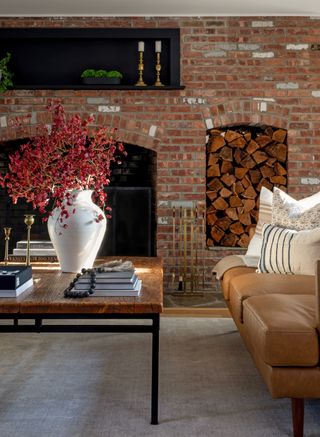 A living room with a textured wall and a large vase with dry flowers placed on a centre table