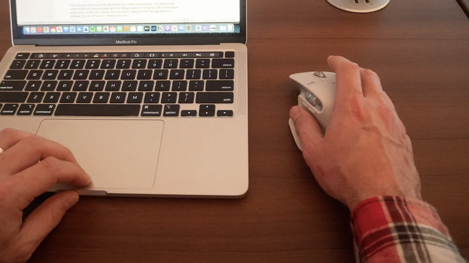 Hand moving mouse next to laptop on desk