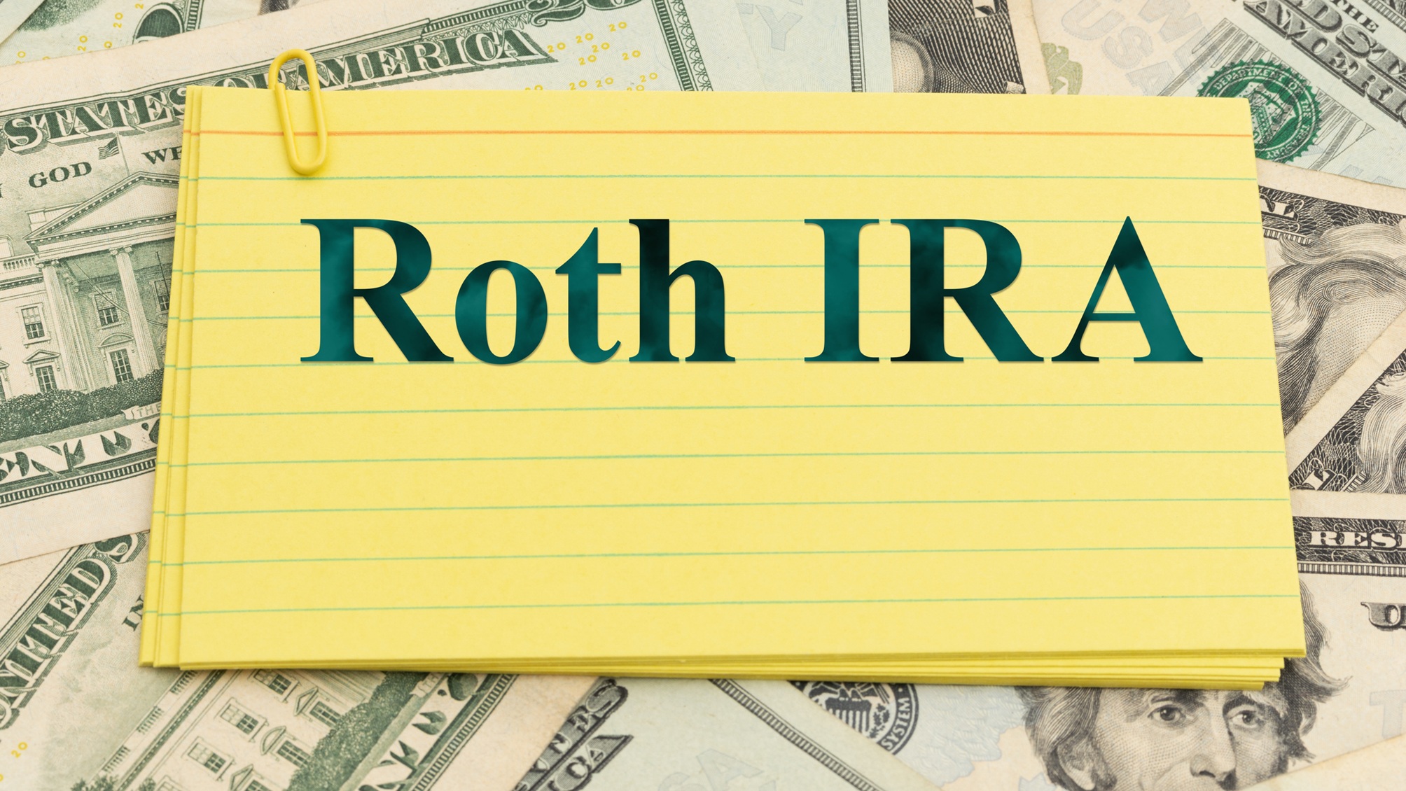 "Roth IRA" written on a yellow index card on top of 20-dollar bills.