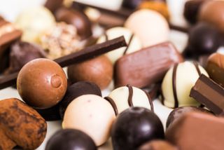 A close up shot of various chocolate truffles: white chocolate, dark chocolate, and milk chocolate are shown.