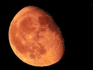 waning gibbous moon close up and orange in color and mars in the top right corner