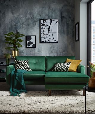 A modern living room with grey walls and emerald green sofa with berber-style rug