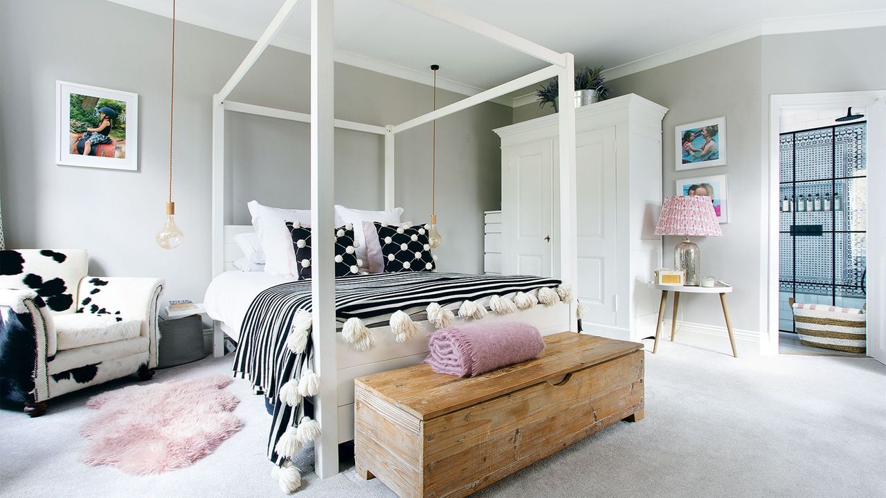 White bedroom with large four-poster bed and glass pendant lights hanging from ceiling