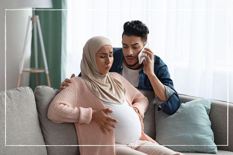 Worried man on the phone as his wife feels contractions before labour