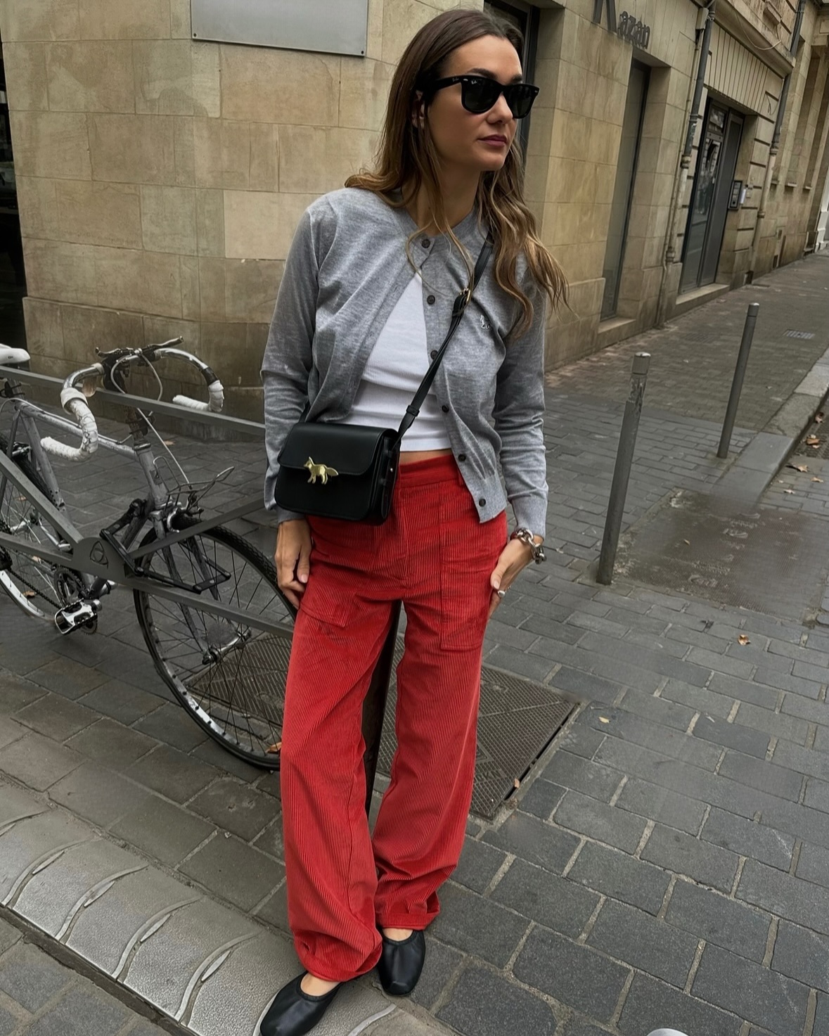 An image of @annelauremais wearing a grey cardigan, one of the leading cardigan colour trends of 2025, with red cord jeans and glove ballet flats.