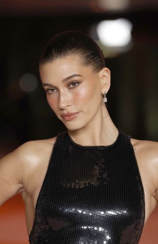 Hailey Bieber on a red carpet in a sequin dress with glowy skin