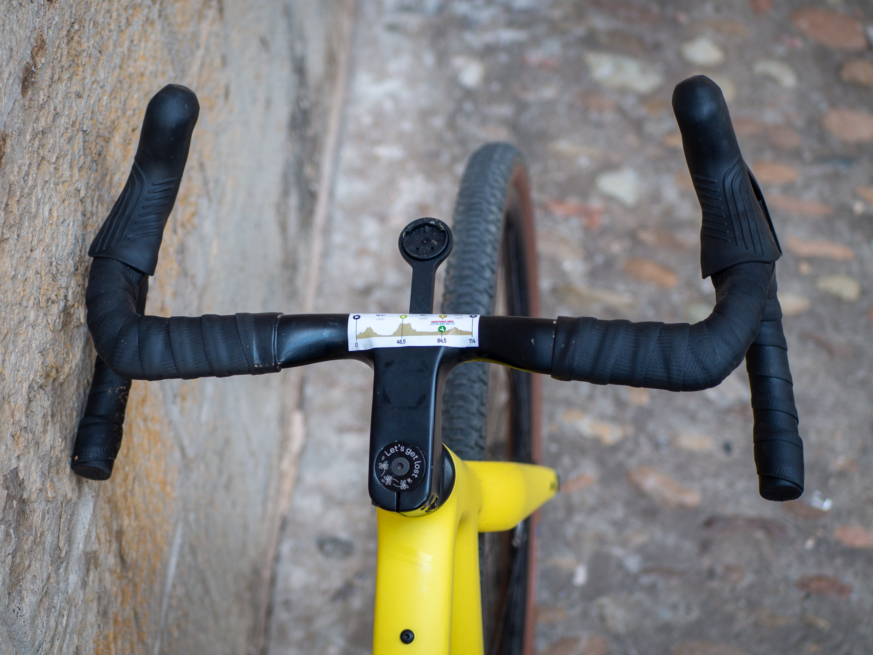 A yellow Guava Spot gravel bike leans against a wall