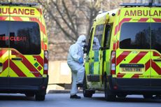 A member of the ambulance service wearing personal protective equipment is seen leading a patient (unseen) into an ambulance at St Thomas' Hospital in London on March 24, 2020.