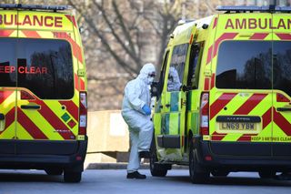 A member of the ambulance service wearing personal protective equipment is seen leading a patient (unseen) into an ambulance at St Thomas' Hospital in London on March 24, 2020.