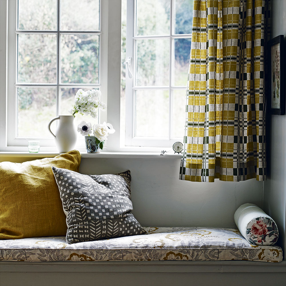 window seat with floral cushions mustard yellow and retro curtain on window