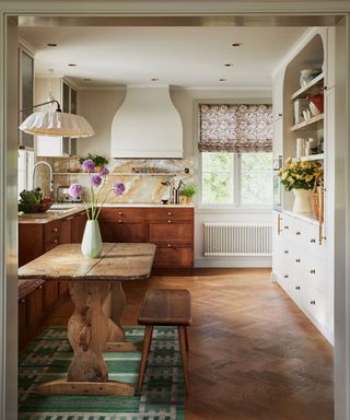 small galley kitchen with neutral upper cabinets and wood lower cabinets with a small antique breakfast table