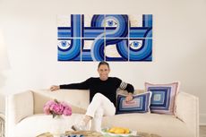 Jonathan Adler sat on a cream sofa with blue abstract art on the walls