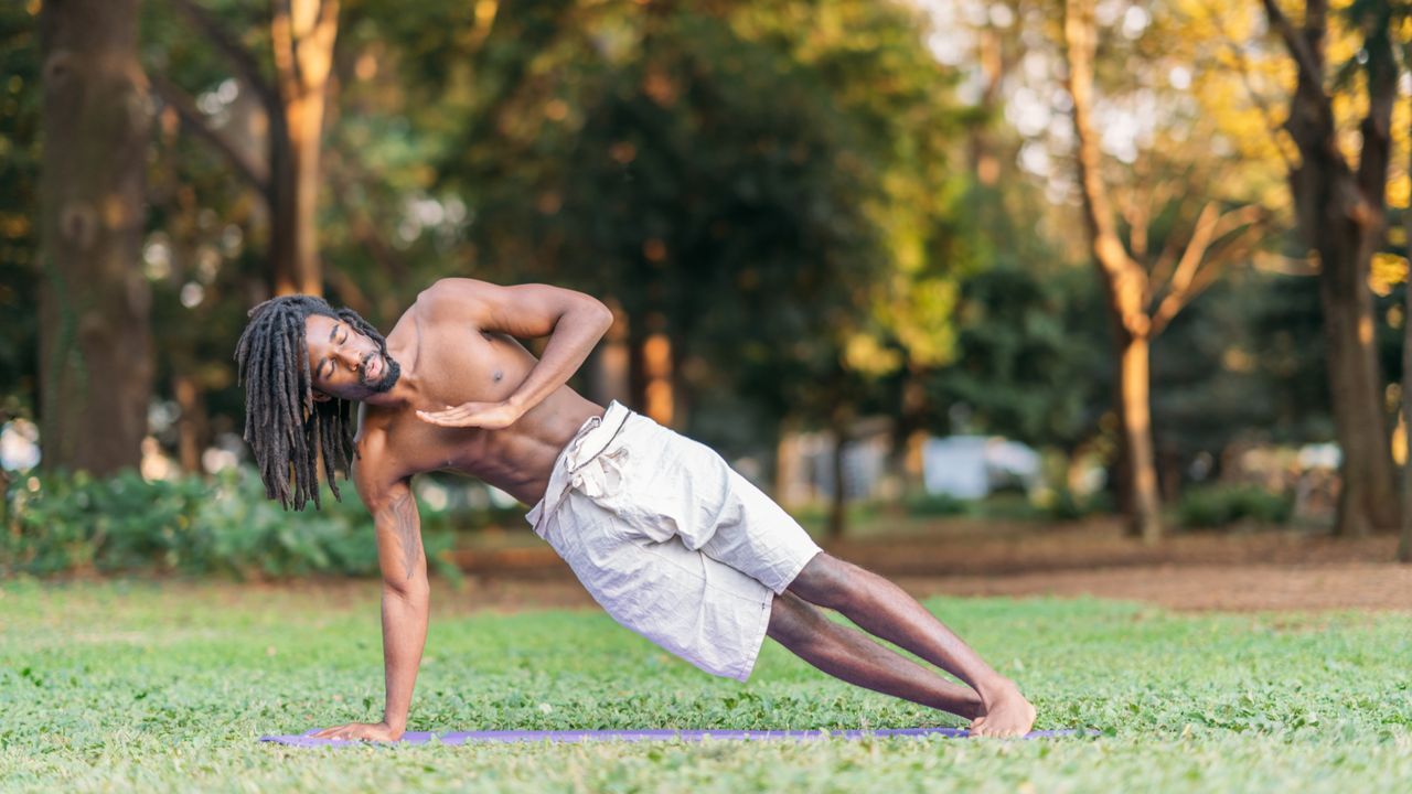 Young black male sportsperson exercising on yoga mat 