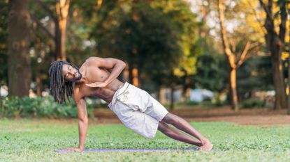 Young black male sportsperson exercising on yoga mat 
