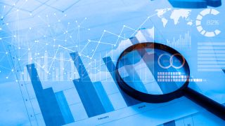 Magnifying glass and documents with analytics data lying on table