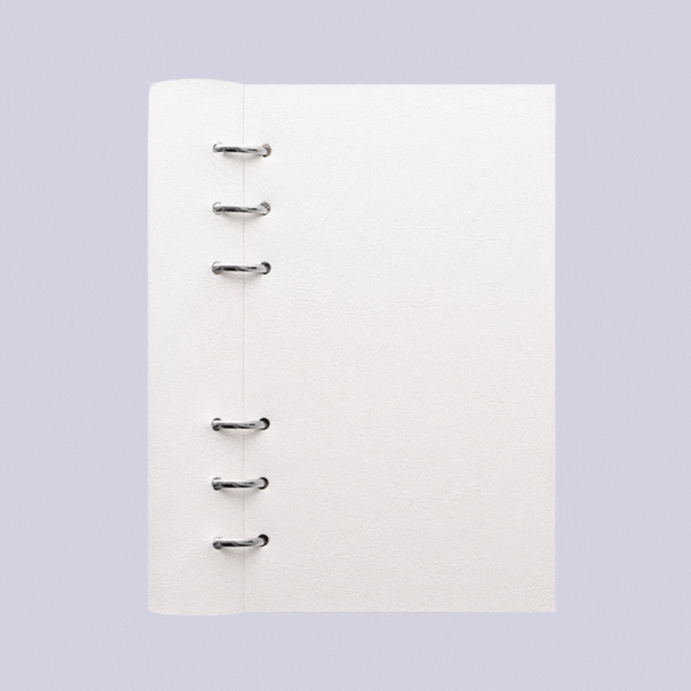 A white organiser with chrome hoops and lined pages against a lilac background is captured in a gif that shows it both closed and open.