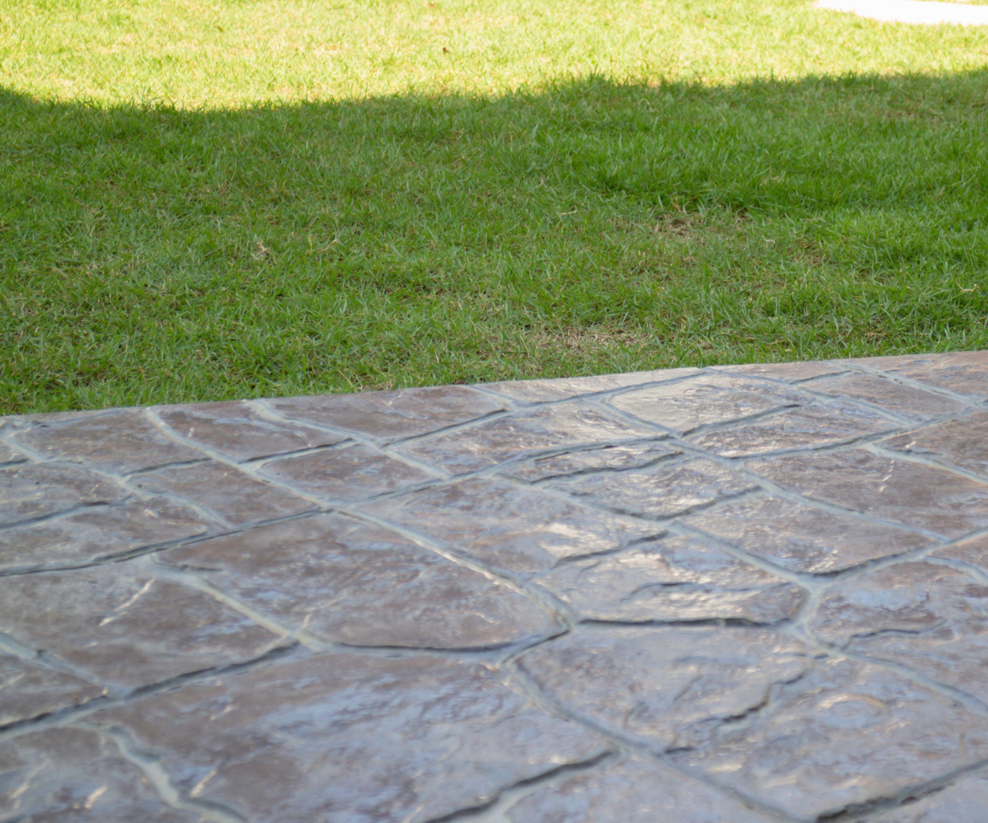 Stamped concrete driveway with grass in background