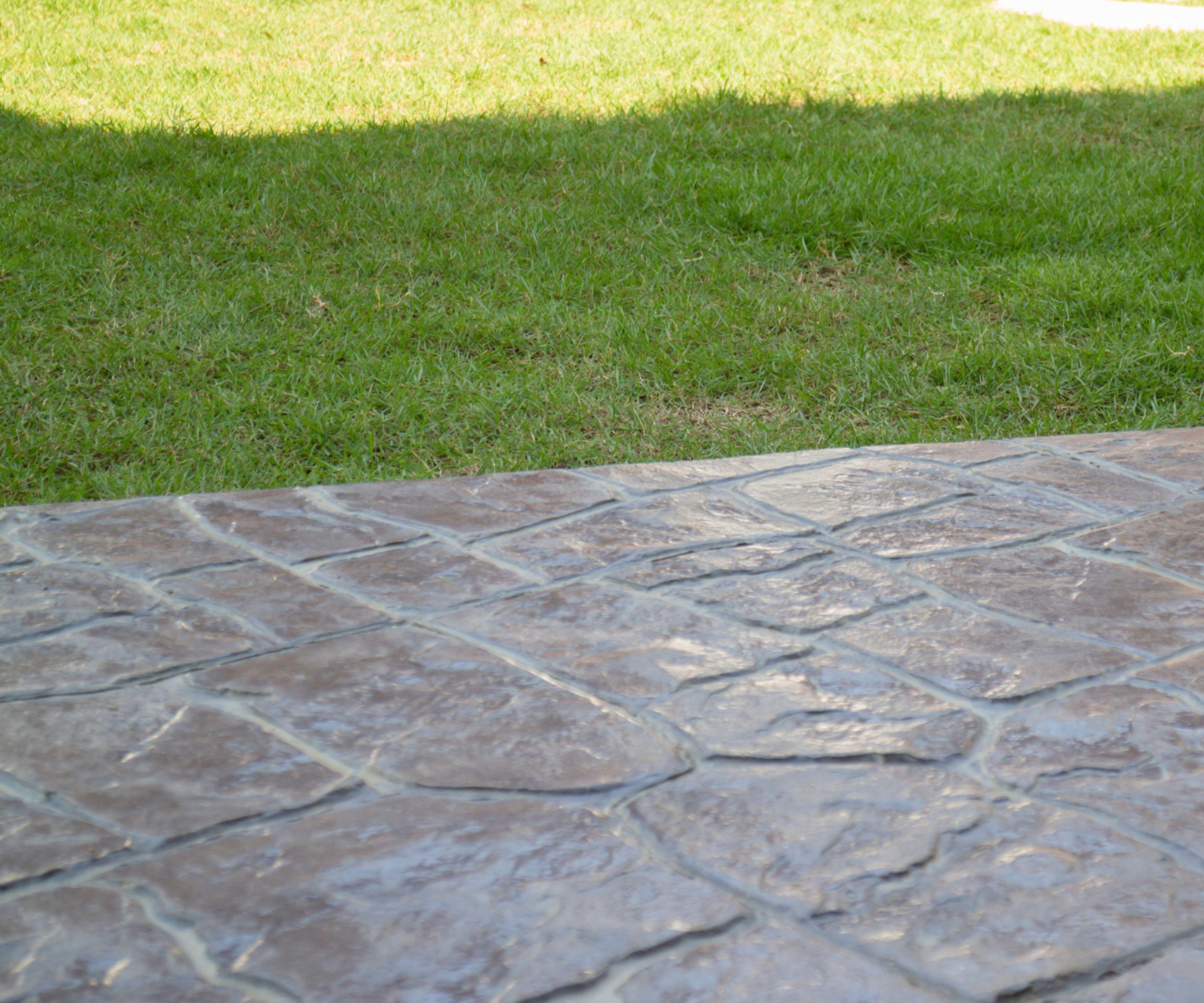 Stamped concrete driveway with grass in background