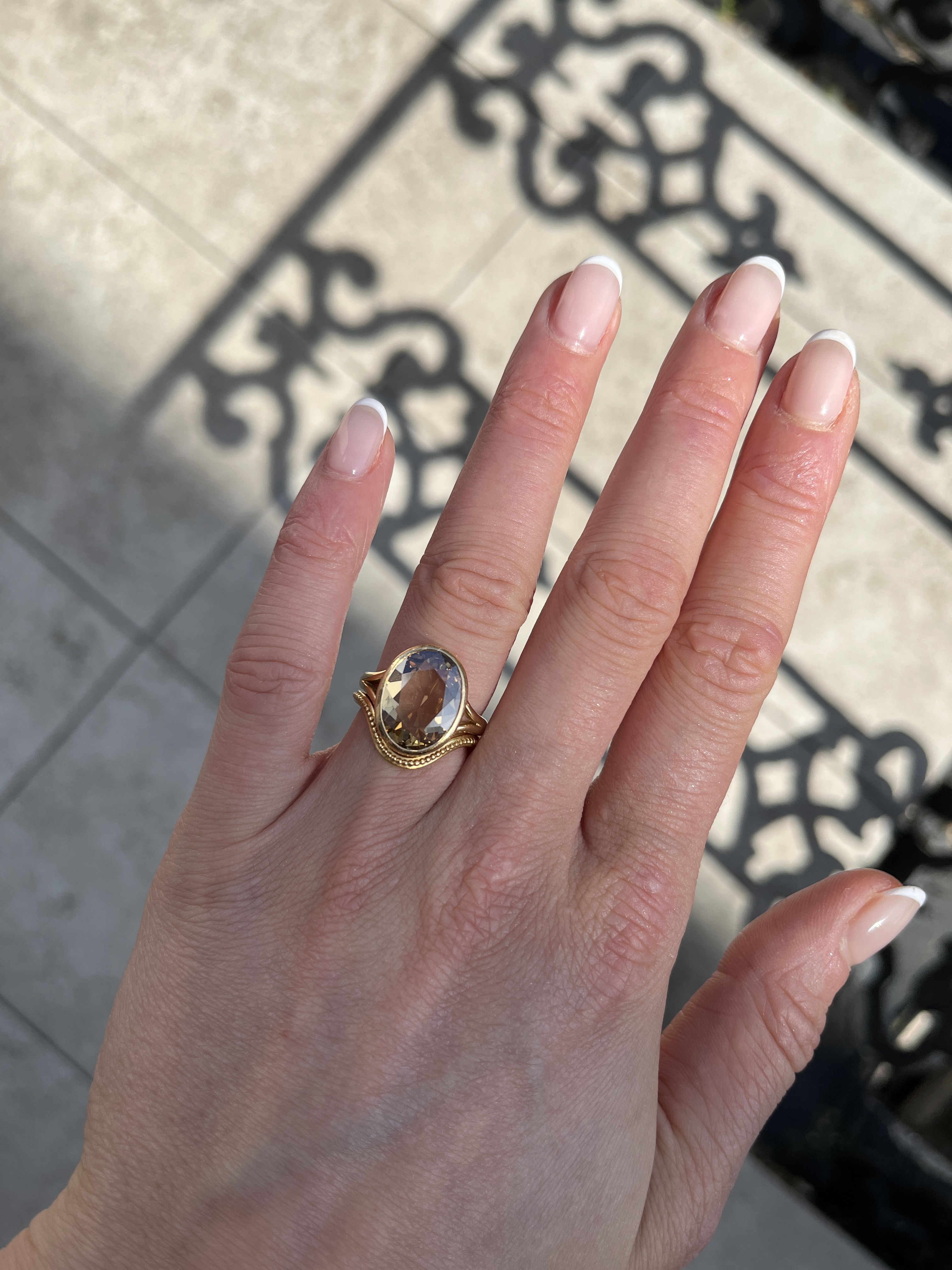a close up of serena ansell's hand showing a brown diamond oval engagement ring and curved wedding band