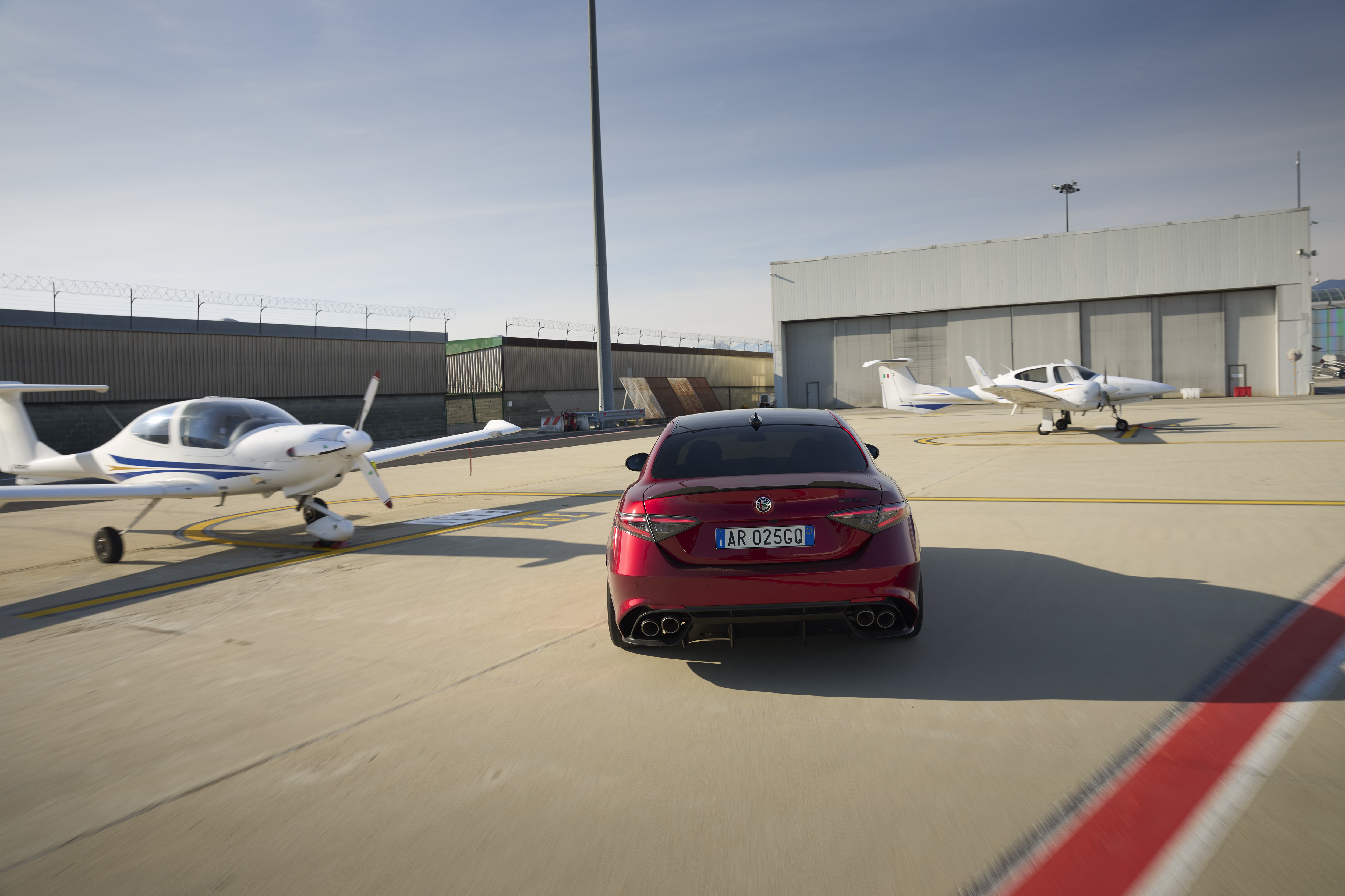 A red Alfa Romeo Giulia zooming about on an airfield