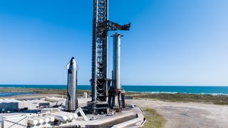 a silver rocket and silver spacecraft stand vertically next to a seaside launch tower