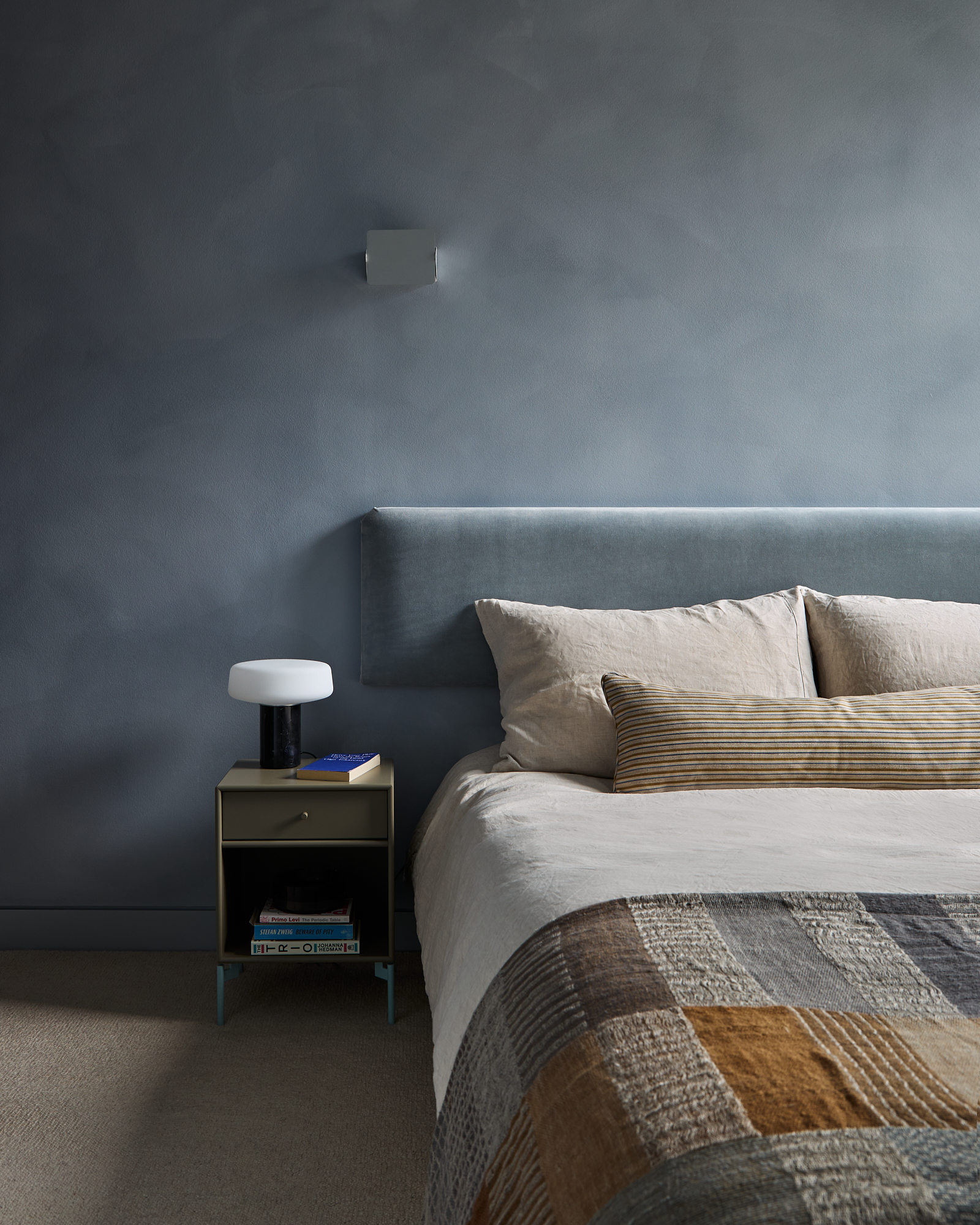 silvery blue bedroom with Bauwerk limewash paint, matching headboard and patchwork throw
