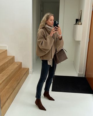 Anouk Yve in a brown jacket, black jeans, and brown boots.