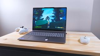 The Lenovo Yoga 7i 2-in-1 16 on a wood table with a mouse and controller running Risk of Rain 2