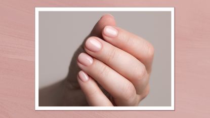 A close up of a hand with a pale pink, glossy manicure and tidy cuticles/ in a pink template