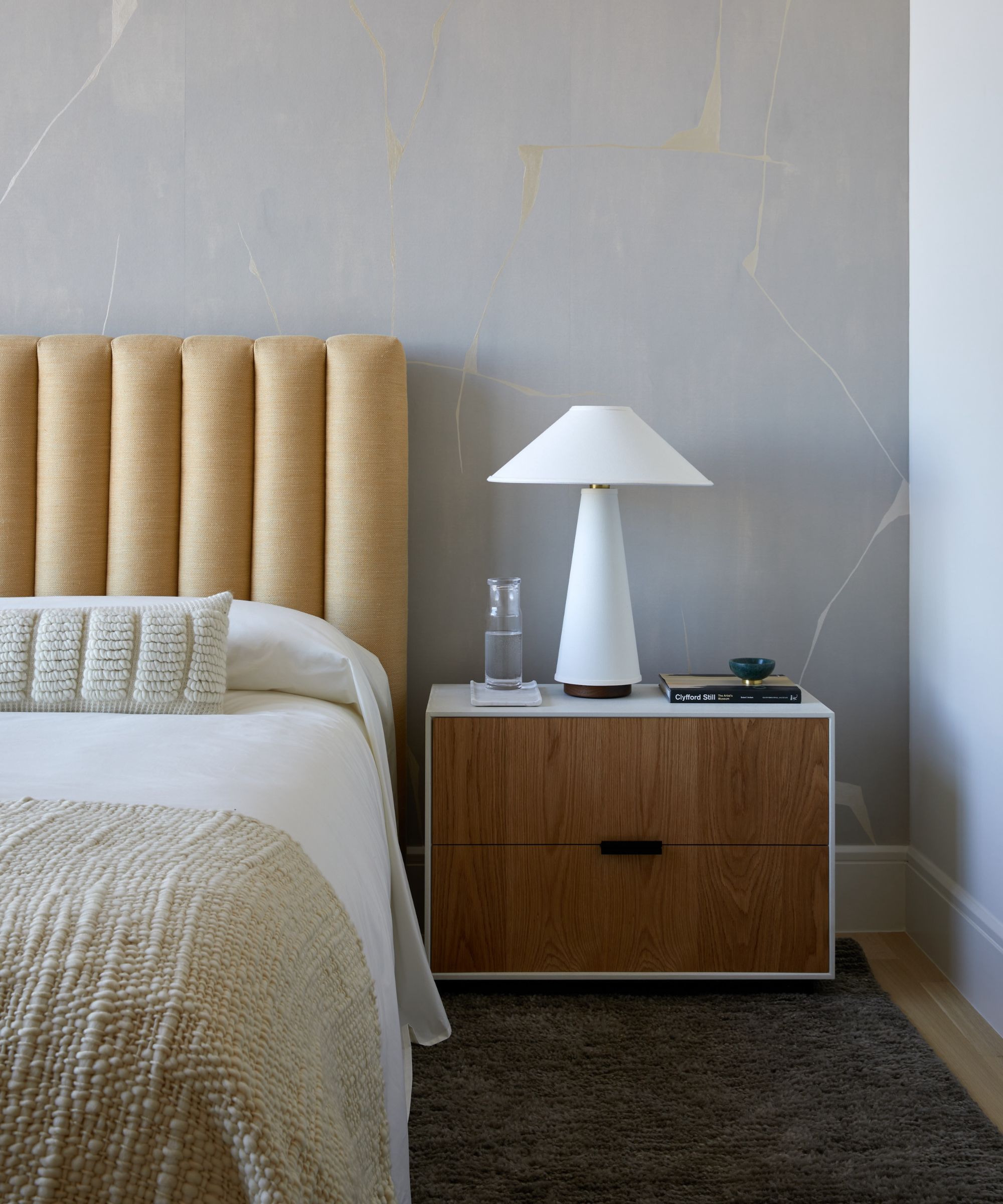 corner of bedroom with light gray walls and butter yellow headboard