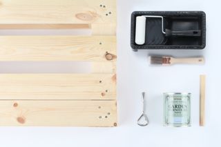 a picture of a pallet, outdoor garden furniture paint, small roller and tray, a small paintbrush and a screwdriver