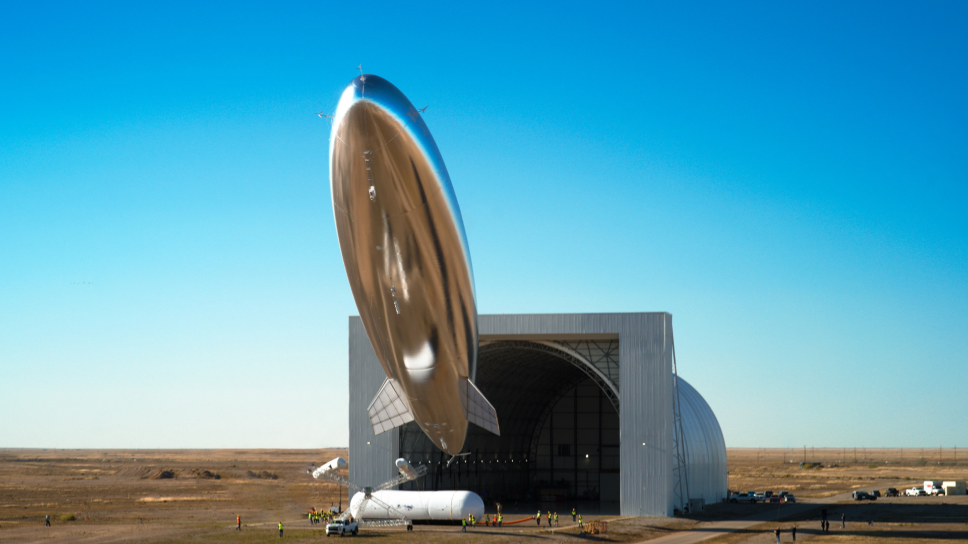 A silvery blimp shape satellite seems to float above the desert of New Mexico
