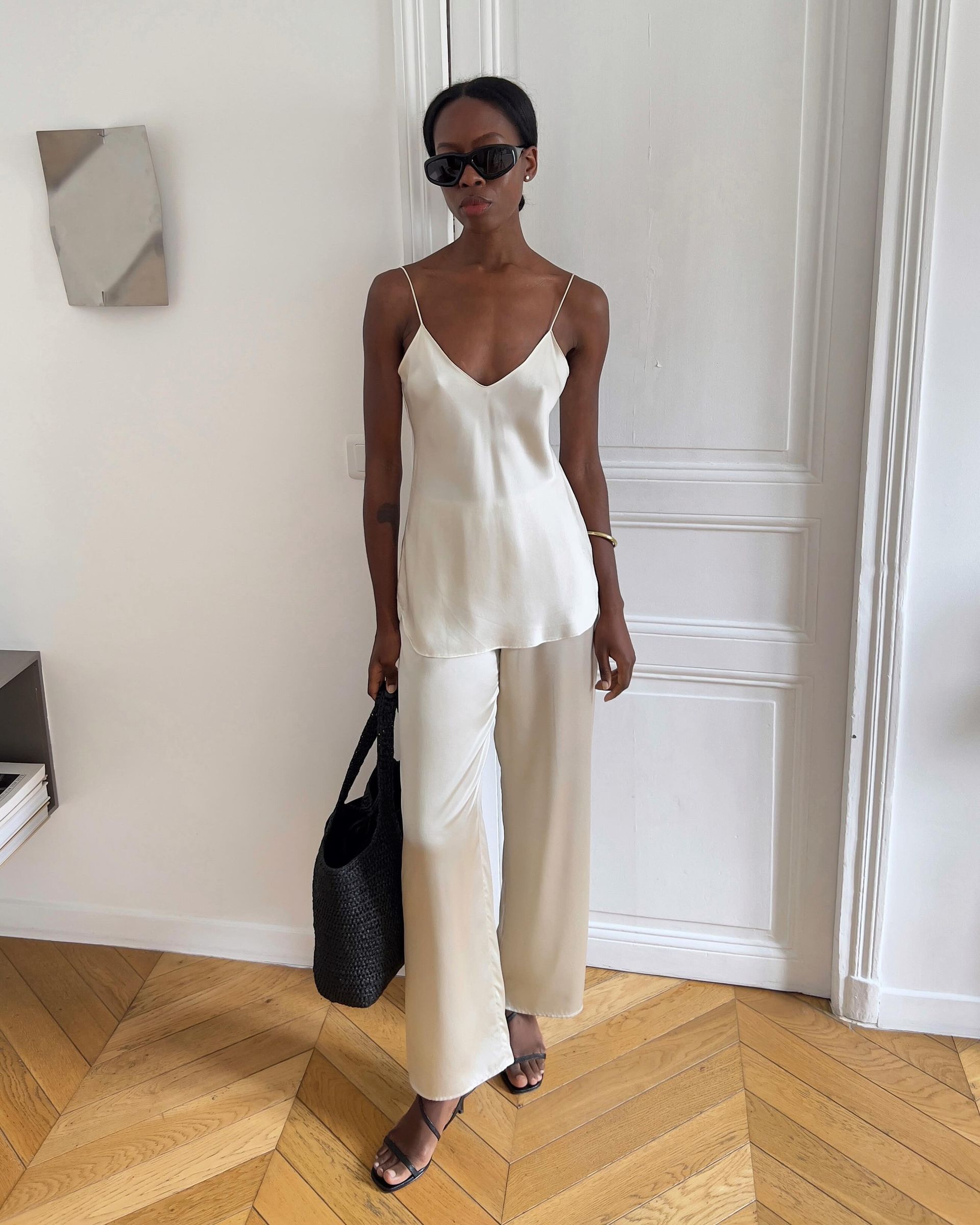sylvie wears a white camisole and white silk pants.