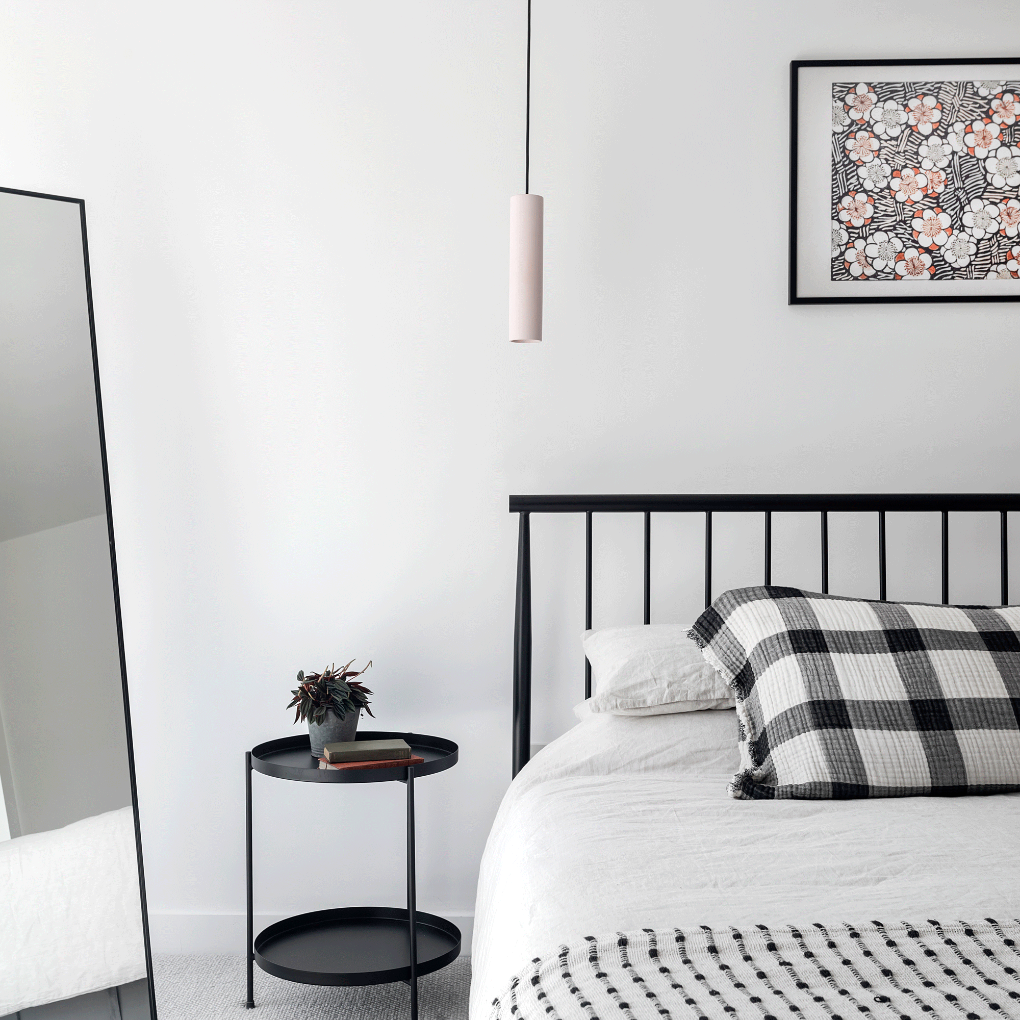a monochrome bedroom with black and white bedding white walls and a black bedframe