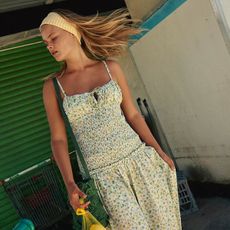 a model wears a yellow headband and a sleeveless floral dress