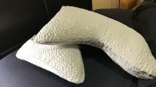 Two white Nest Bedding Easy Breather Side Sleeper pillows stacked on top of each other on top of a made bed