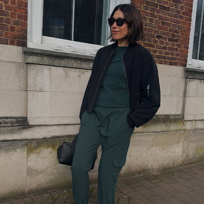 Lucy wears green sweatsuit and black bag and jacket. 
