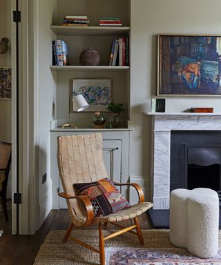 A light green room with bookshelves and an armchair in front of a fireplace