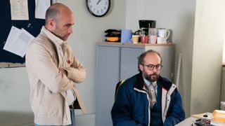 Teddy Mitchell and Reiss Colwell look at a computer in EastEnders. 