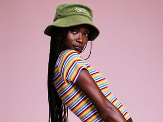 a model wears a green bucket hat and a striped short-sleeve T-shirt