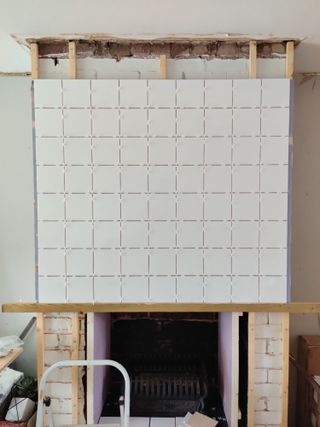a fireplace with new white tiles being added