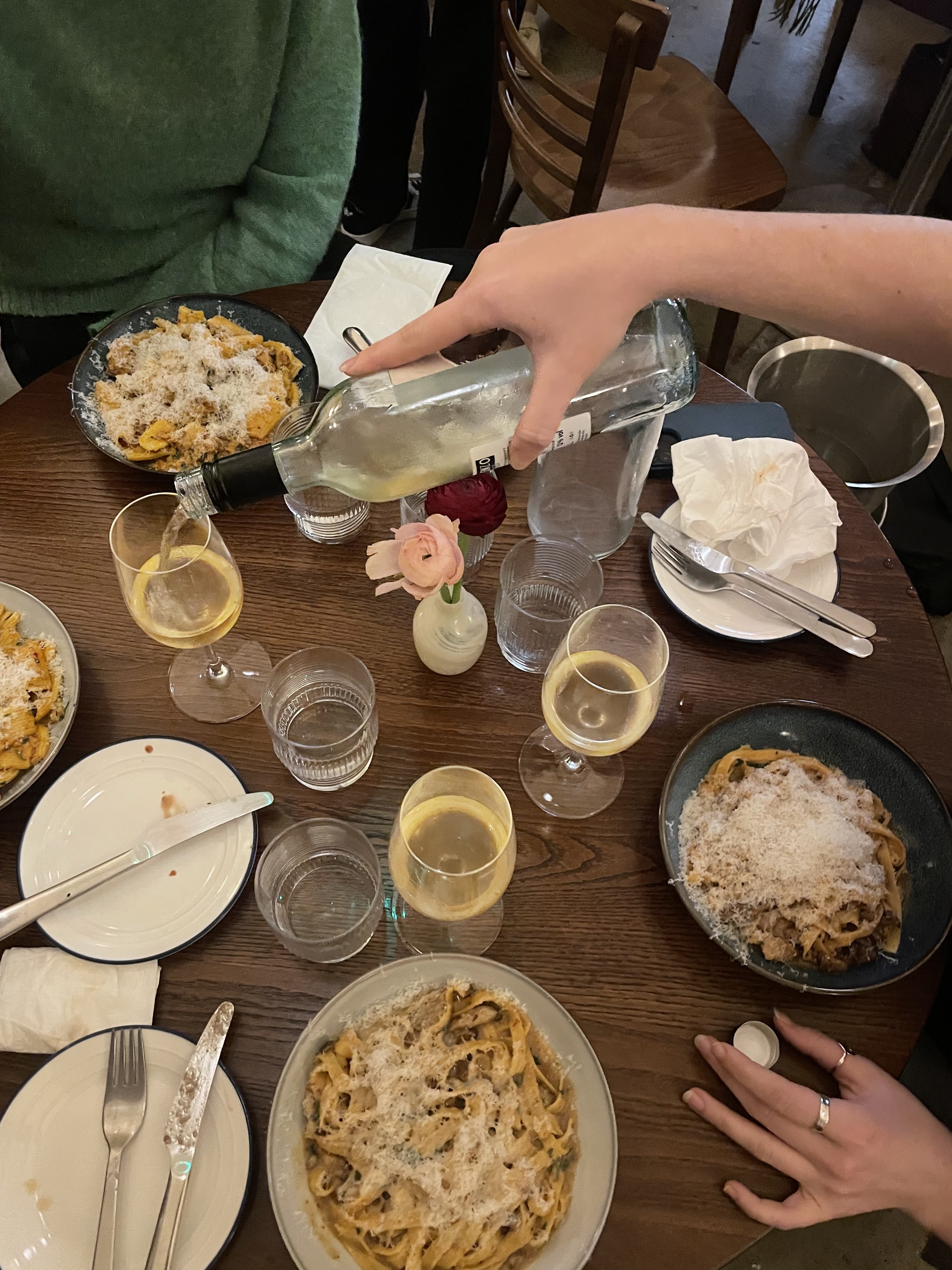 an image of the table at tom's pasta with four plates of tagliatelle and wine