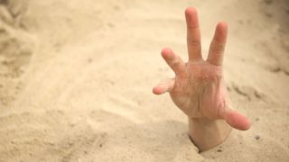 A hand reaching out of quicksand