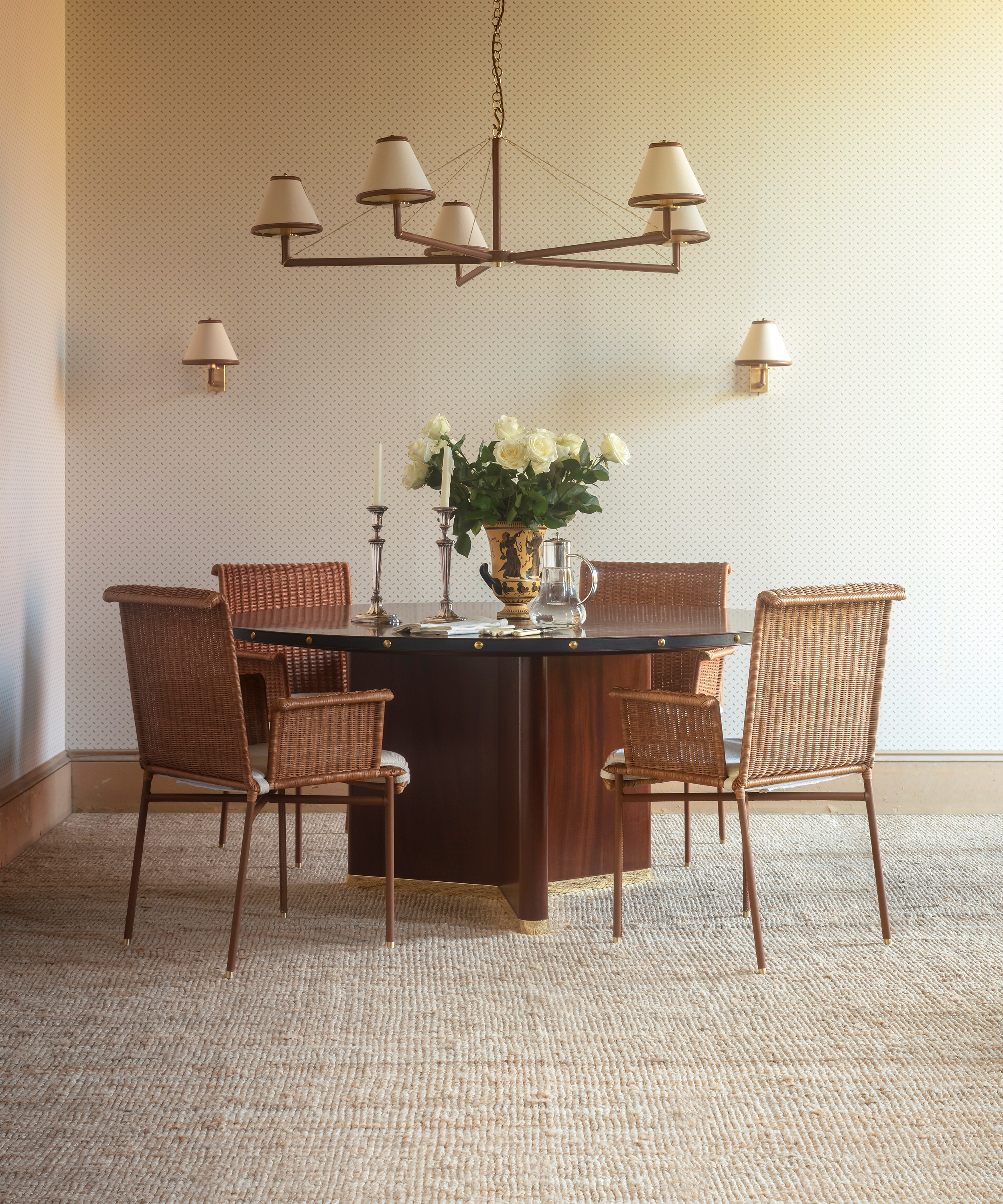 rattan dining chairs grouped around a round wood dining table on a beige rug