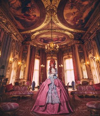 The Governess – a person dressed smartly in a large dress in retro fashion in the historic Belvoir Castle reception room